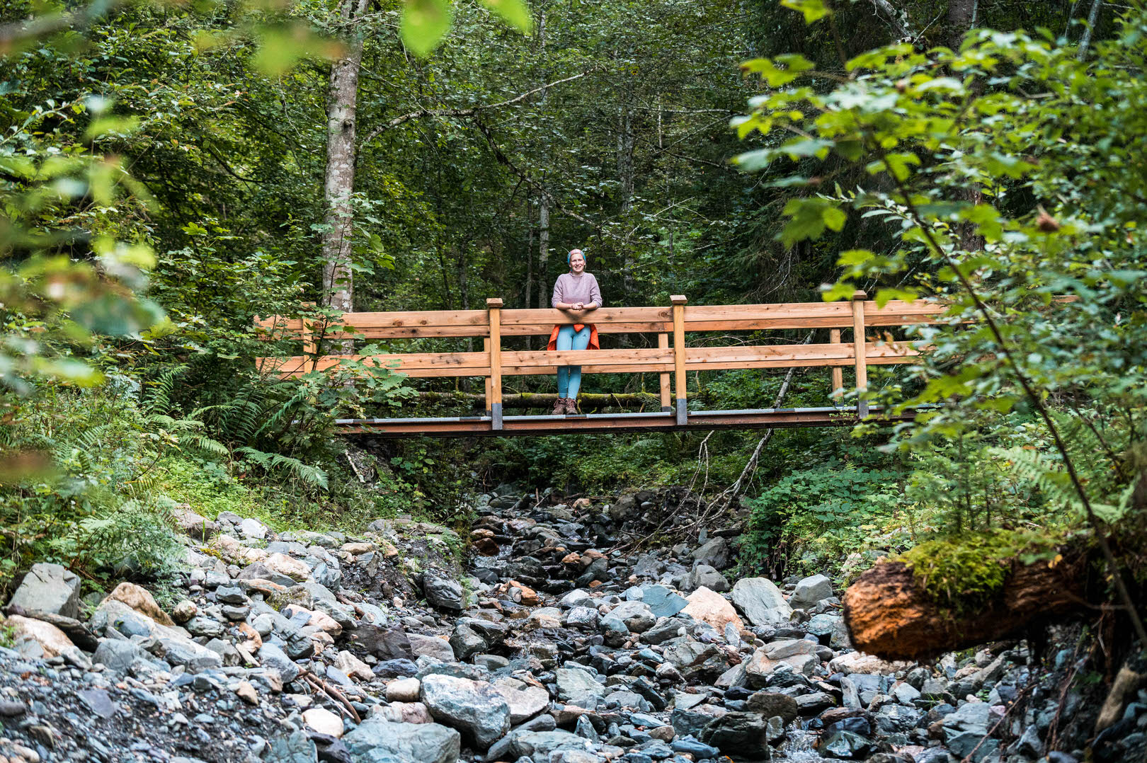 Wandererin im Wald auf Holzbrücke über Bach
